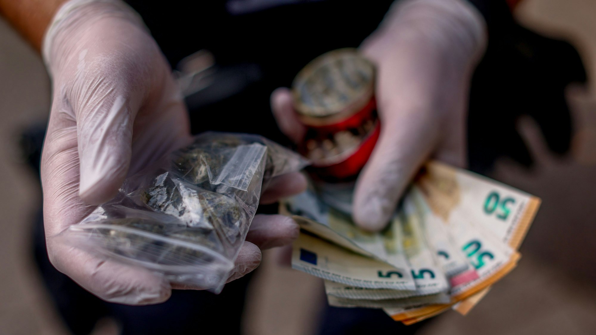 Ein Polizist zeigt eine sichergestellte Tüte Haschisch und Drogengeld während einer Razzia der Polizei gegen Drogendealer am Ebertplatz in Köln.