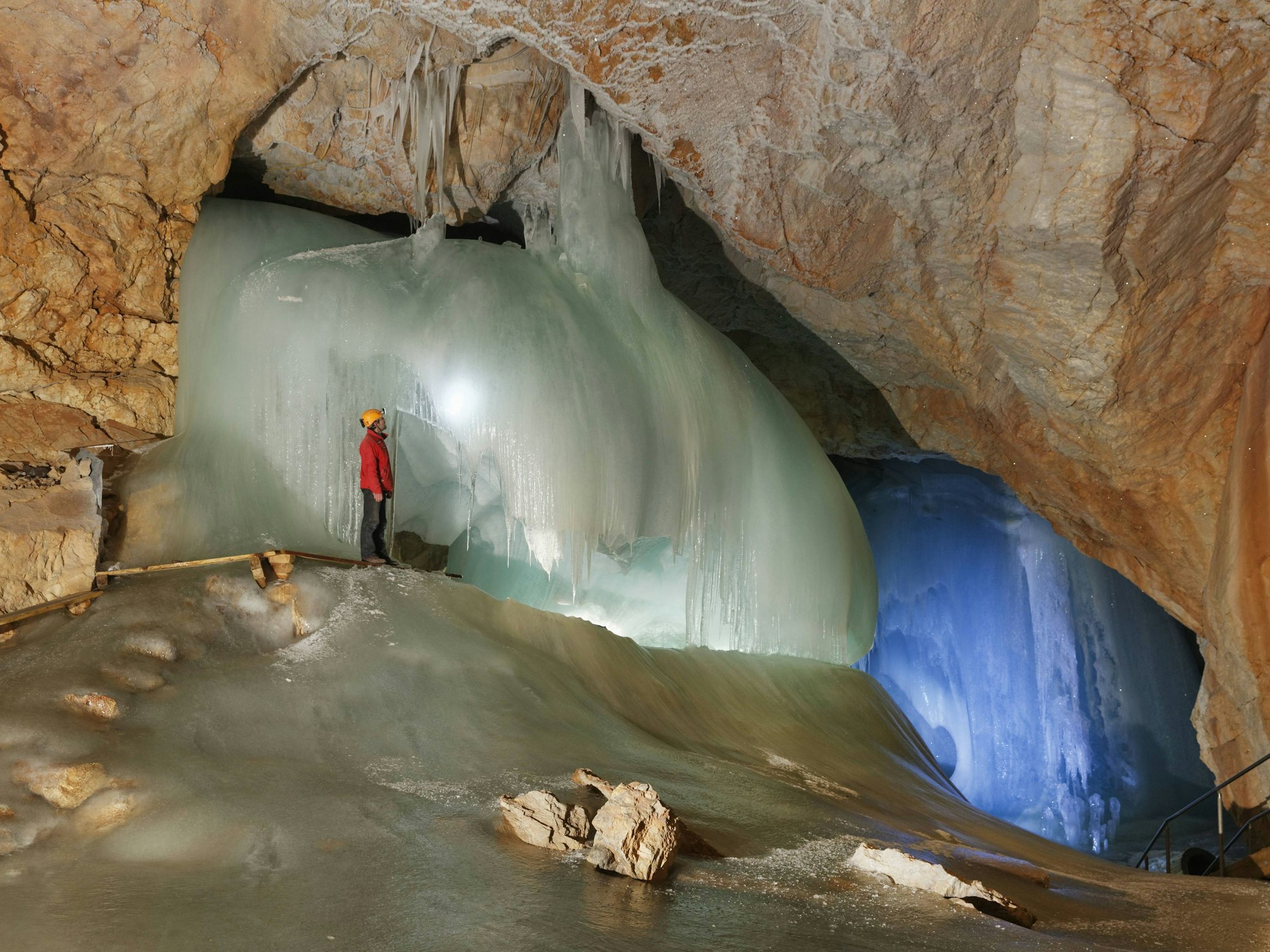 Eine Person mit Helm steht im Juli 2014 neben einem riesigen Eisvorhang in der Eisriesenwelt in Österreich.