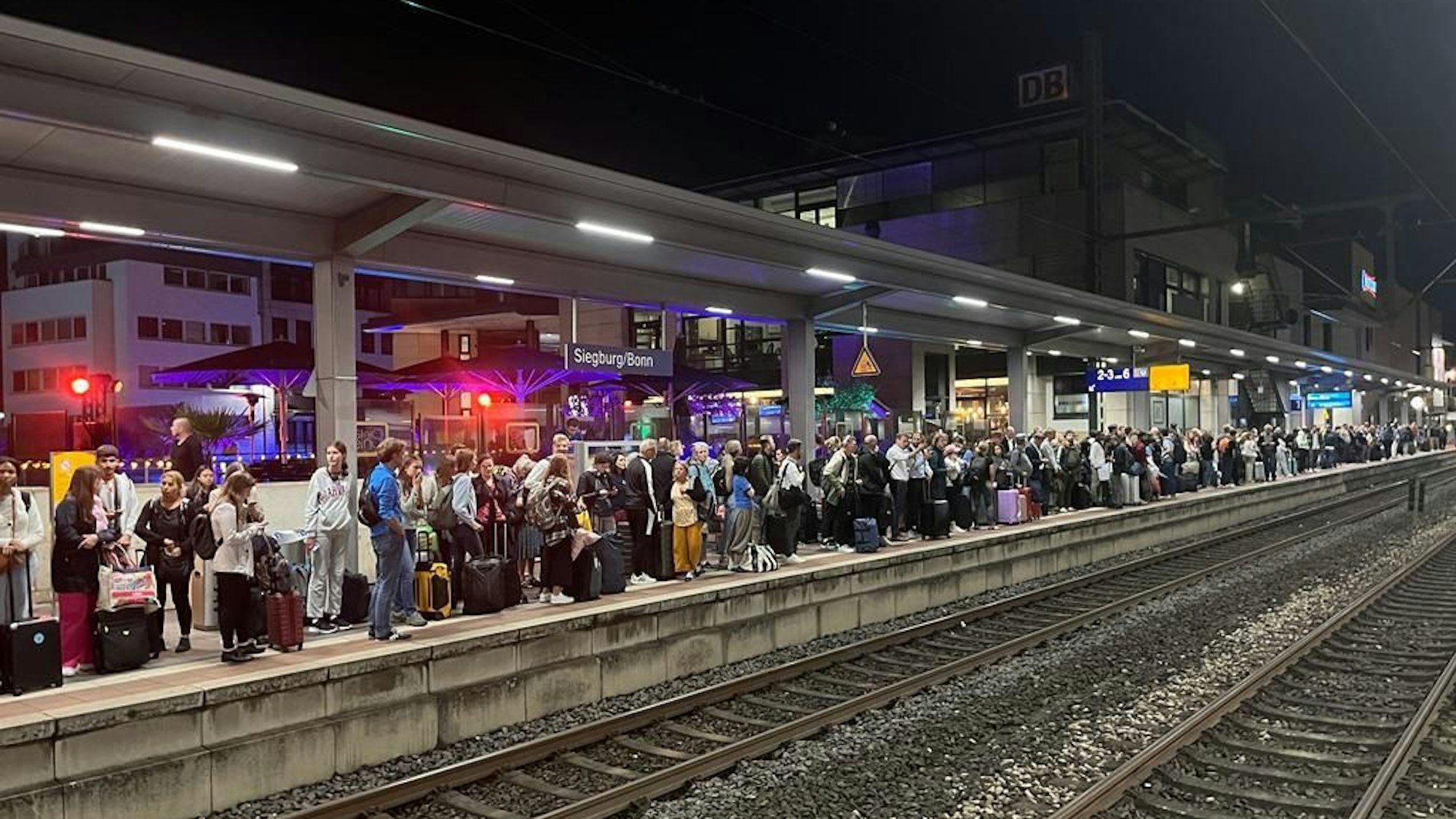 Hunderte Menschen stehen an einem Bahngleis.
