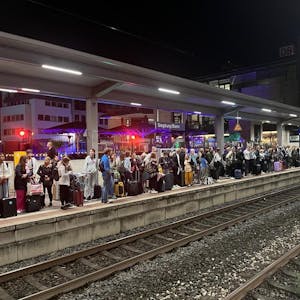 Hunderte Menschen stehen an einem Bahngleis.