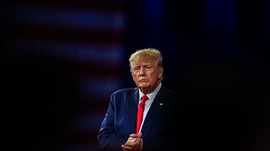 Donald Trump mit blauem Anzug und roter Krawatte bei einer Konferenz im Februar 2022.