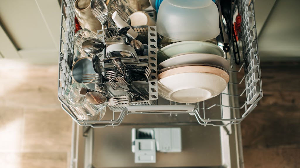 Auf dem Foto sieht man einen offenen Geschirrspüler mit sauberem Geschirr.