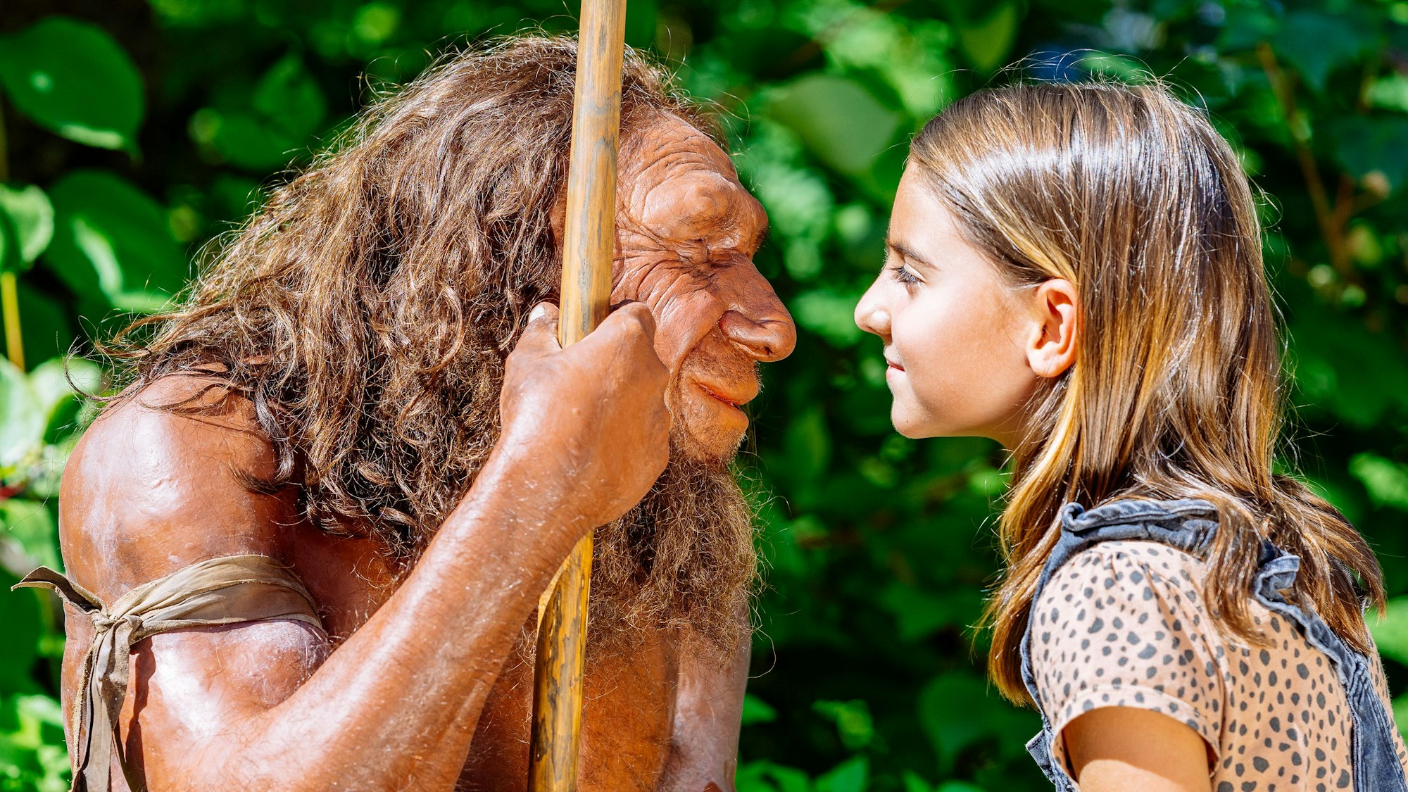 ein Mädchen steht der Figur eines Neanderthalers gegenüber