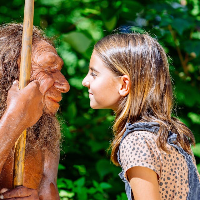 ein Mädchen steht der Figur eines Neanderthalers gegenüber