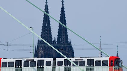 Eine Straßenbahn der Kölner Verkehrsbetriebe (KVB) fährt über die Severinsbrücke vor der Kulisse des Kölner Doms.