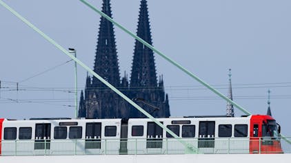 Eine Straßenbahn fährt über die Rheinbrücke. Im Hintergrund ist der Kölner Dom.