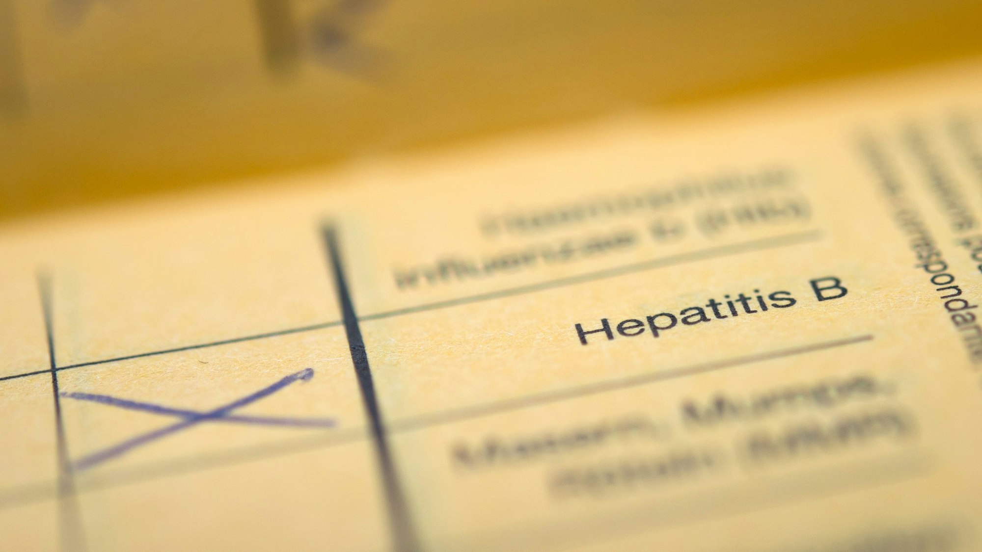 Auf einem gelben Impfpass ist neben dem Schriftzug „Hepatitis B“ ein handgemaltes Kreuz in blauer Farbe zu sehen. Die Zahl der Infektionen mit Hepatitis B und C ist laut Angaben des Robert-Koch-Instituts deutlich gestiegen. (Symbolbild)