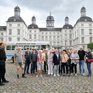 Eine Gruppe und ein&nbsp; historischer Bus stehen im Innenhof von Schloss Bensberg.