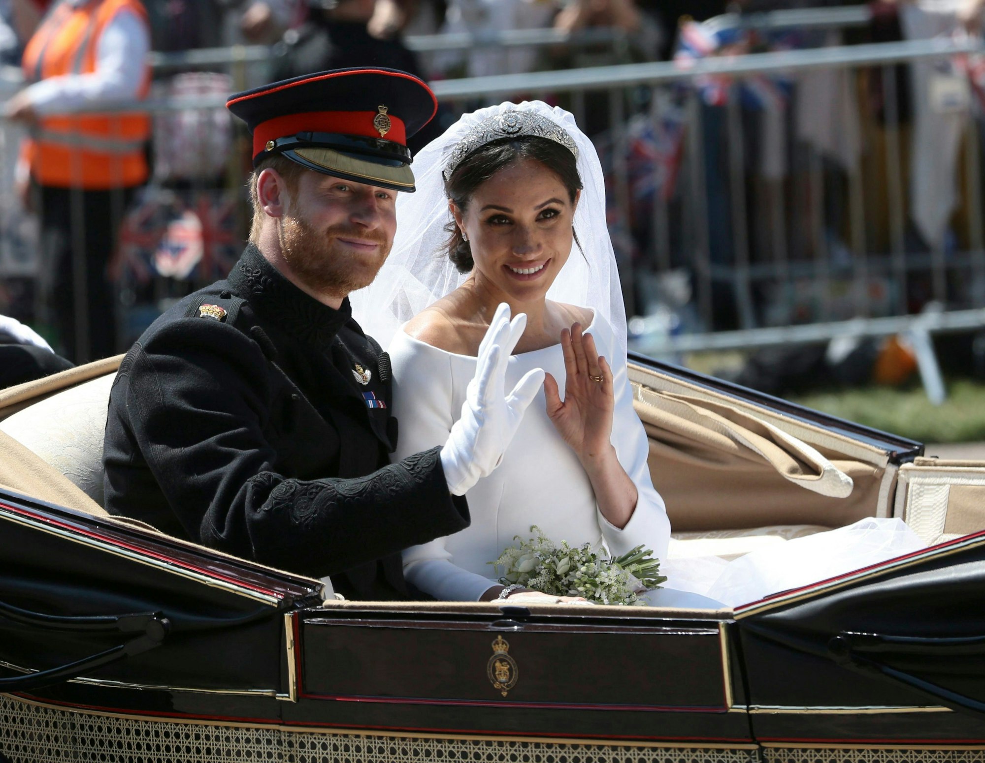 Bräutigam Prinz Harry und seine Braut Herzogin Meghan fahren nach ihrer Hochzeit in einer Kutsche und winken Menschen zu, die den Straßenrand säumen.