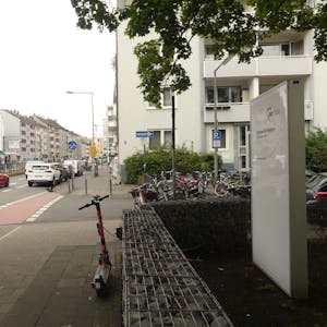 Eine zweispurige Straße mit einer Straßenbahnhaltestelle in der Mitte ist zu sehen. Im Vordergrund steht das Schild der Senioreneinrichtung, die unmittelbar an der Straße liegt.&nbsp;