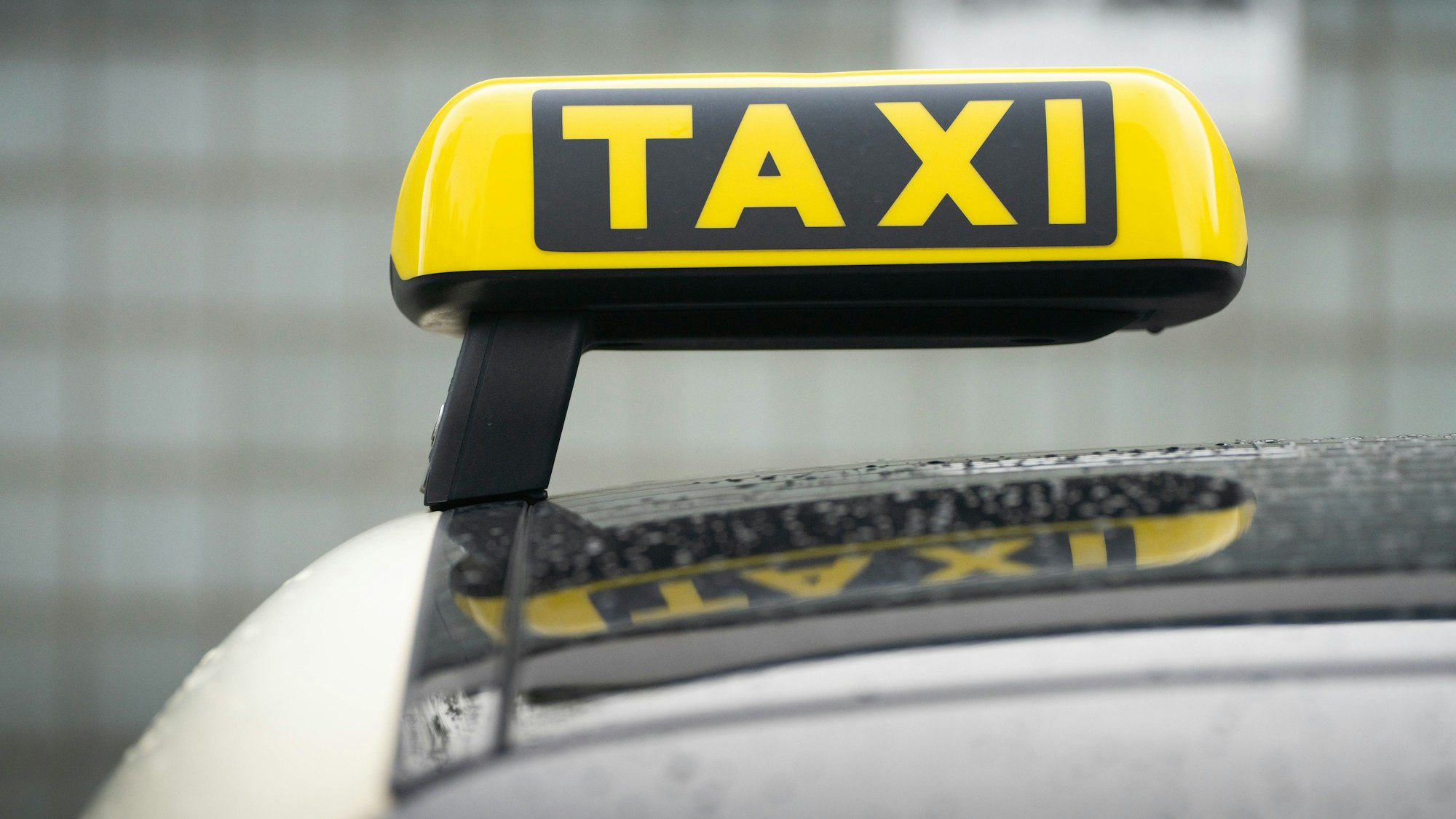 Ein Taxi-Schild ist auf dem Dach eines Fahrzeuges befestigt.