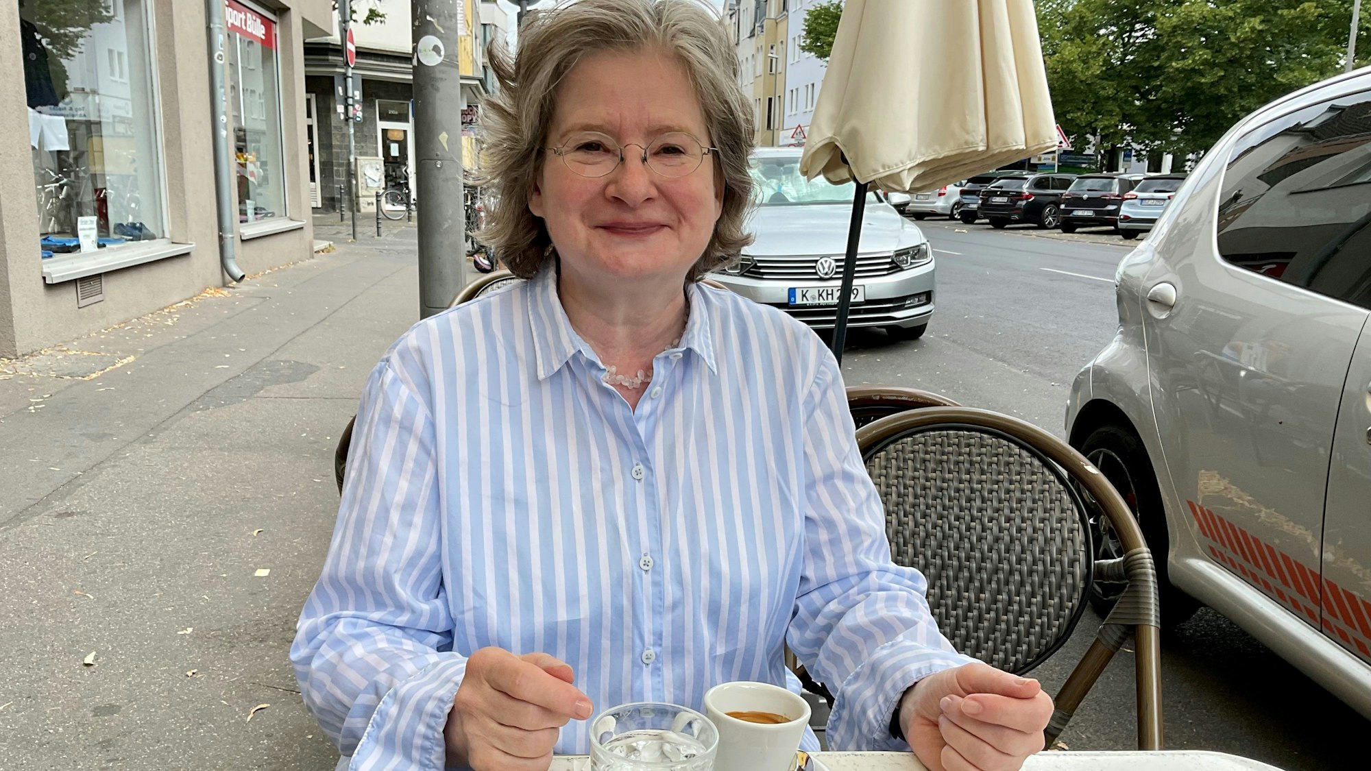 Grauhaarige Frau im Straßencafé mit einem Espresso