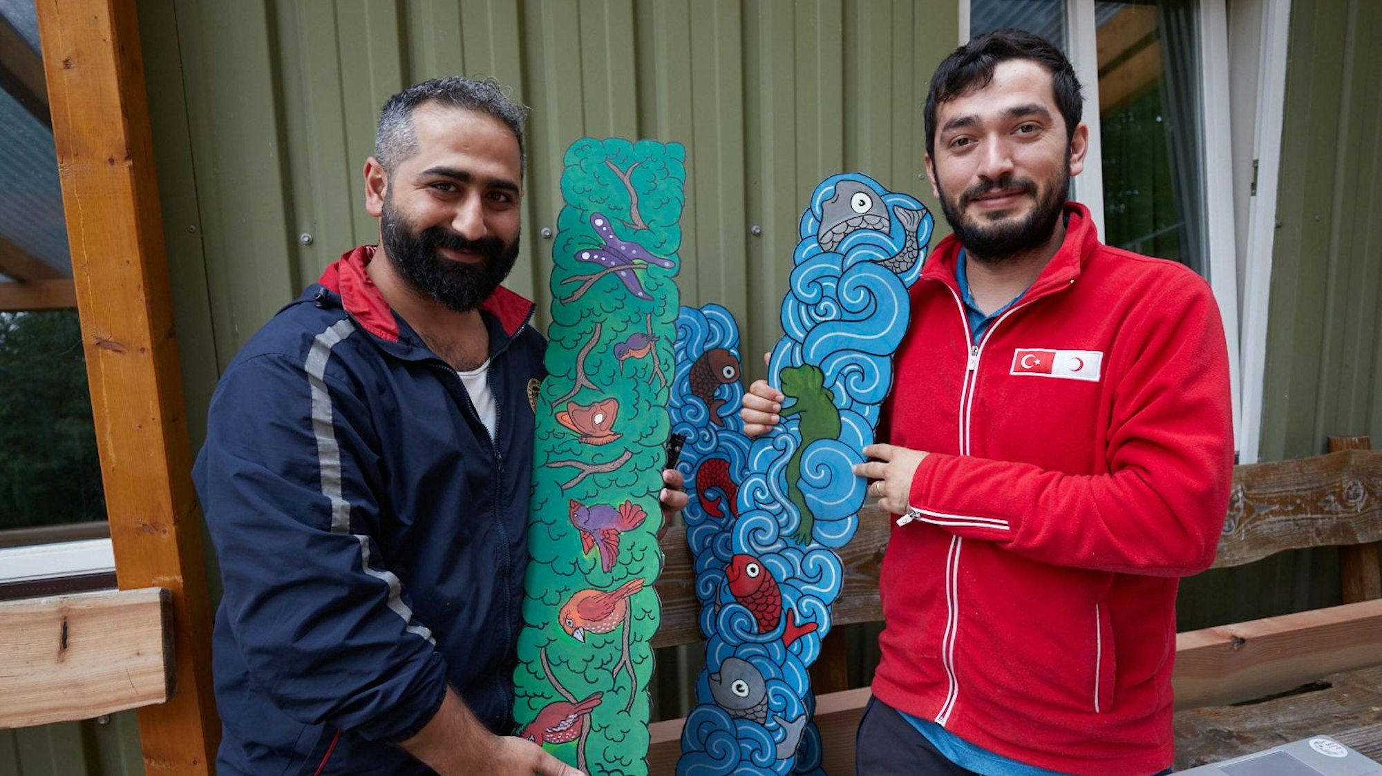 Ibrahim Yildiz und Ahmed Enis Güncan halten Bretter mit „Tierbegegnungen“ in den Händen.