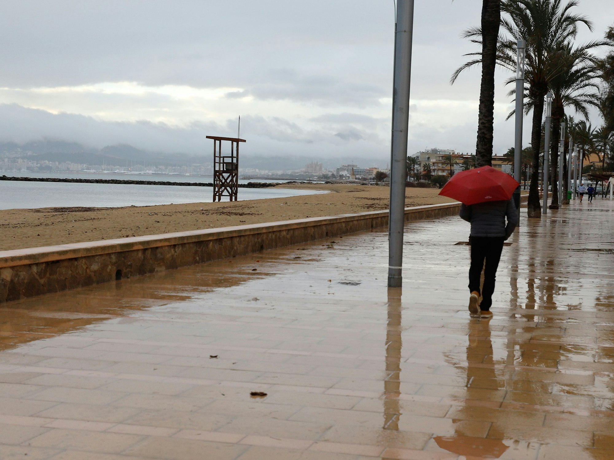 Ein Mann mit Regenschirm am Strand von Palma.