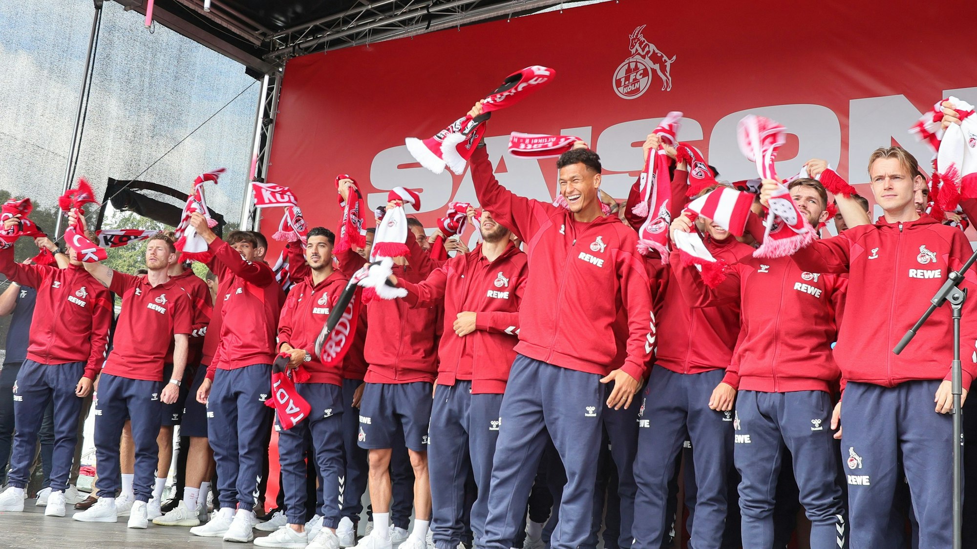 Die Mannschaft des 1. FC Köln singt die FC-Hymne auf einer Bühne.