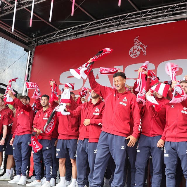 Die Mannschaft des 1. FC Köln singt die FC-Hymne auf einer Bühne.