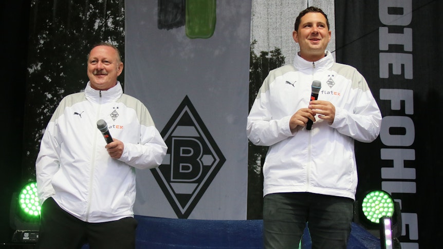 Manager Roland Virkus (l.) und Sportdirektor Nils Schmadtke (r.), hier zu sehen bei der Saisoneröffnung (6. August 2023) von Fußball-Bundesligist Borussia Mönchengladbach. Die beiden stehen auf einer Bühne und halten jeweils ein Mikrofon in ihren Händen.