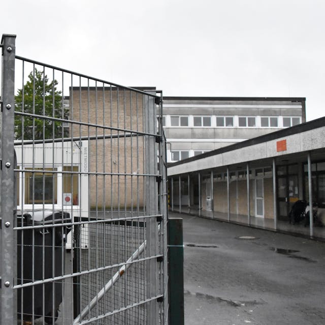 Hinter einem Zaun steht das Schild Gesamtschule. Es weist auf den Haupteingang des Standorts Rosbach hin.