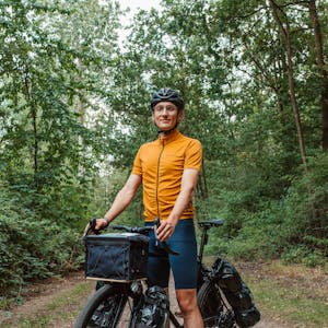 Ein junger Mann sitzt auf einem Fahrrad mit Packtaschen