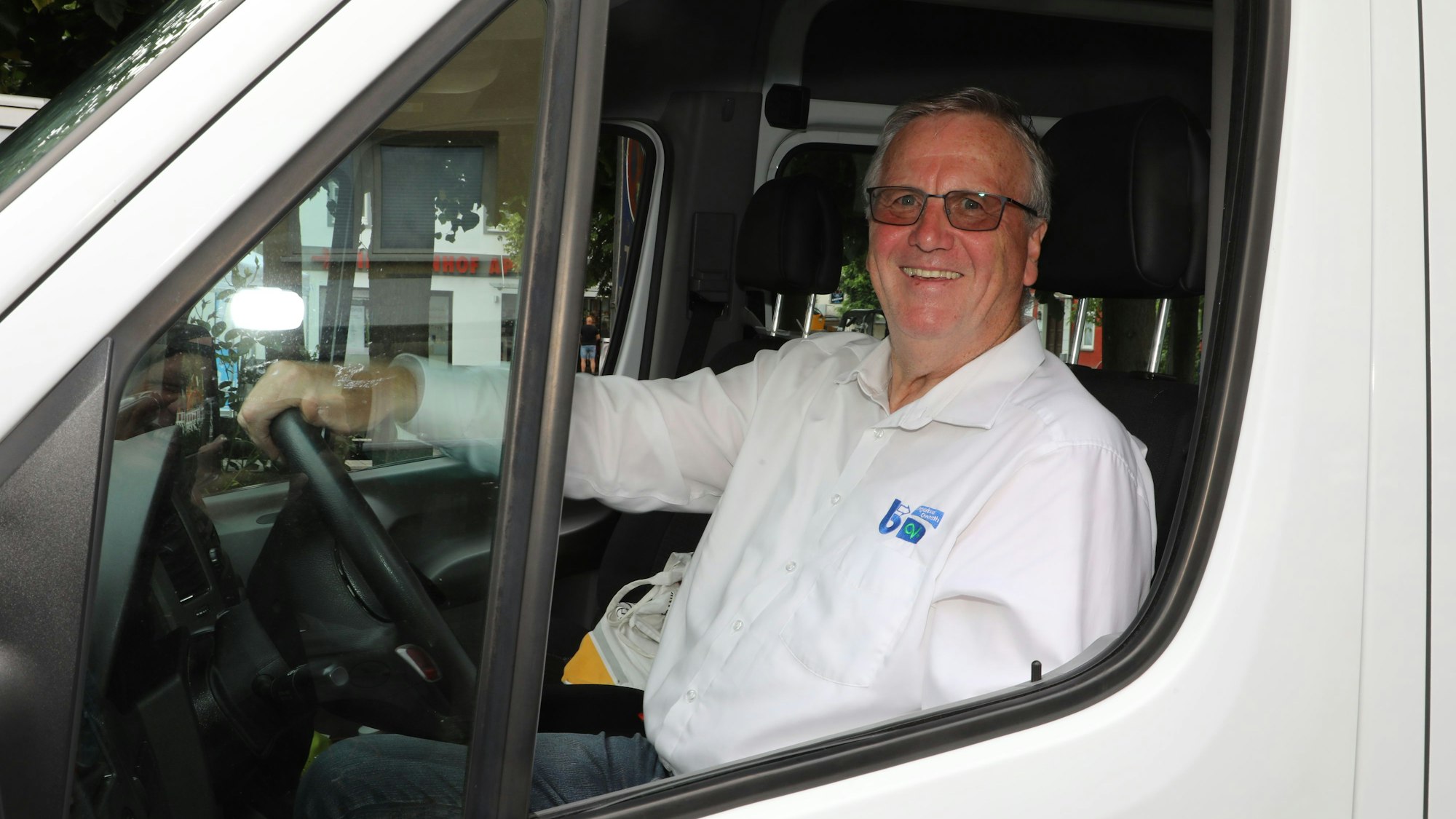 Aloisius Schmidt sitzt am Steuer des Overather Bürgerbusses und lächelt durch das Fahrerfenster.