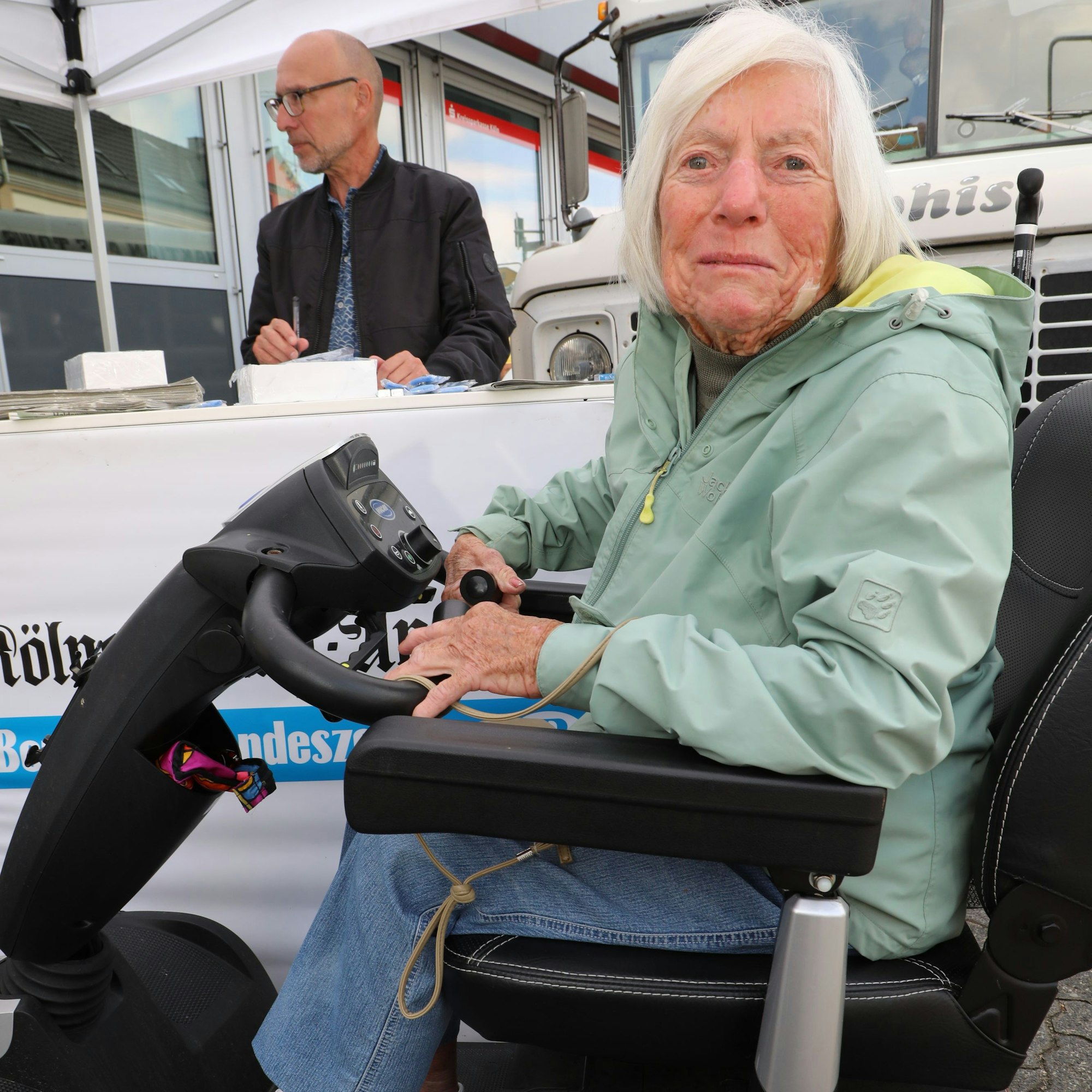 Helga Kozik sitzt in ihrem Rollstuhl am Stand der Lokalredaktion vor dem Hoffnungsthaler Wochenmarkt.