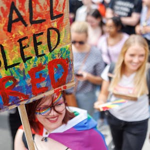 „We all bleed red“ steht auf dem Schild einer Teilnehmerin einer CSD-Demonstration im Rahmen der Nürnberger Prideweek.