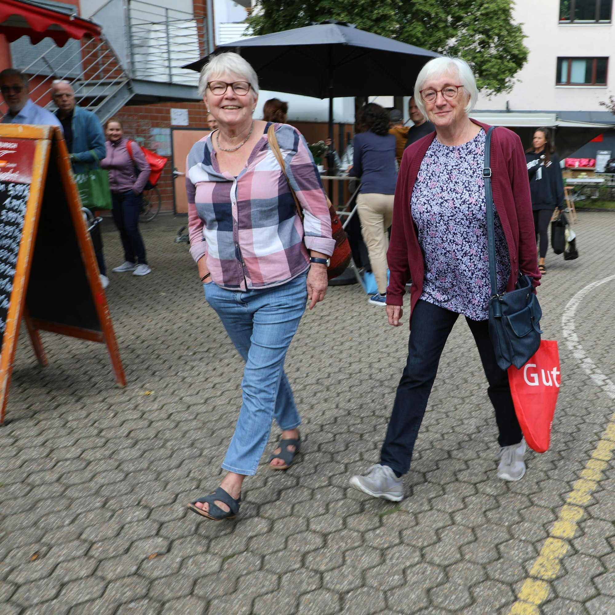 Zwei Frauen gehen auf den Hoffnungsthaler Wochenmarkt.
