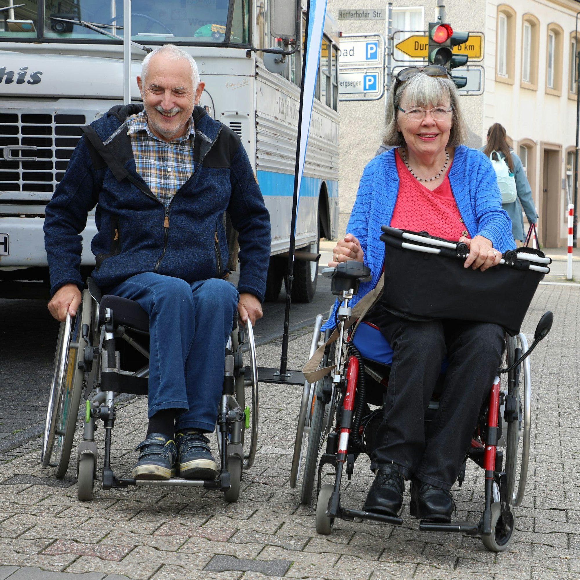 Inge und Jochen Randow fahren mit ihren Rollstühlen über den Gehweg der Hauptstraße in Rösrath-Hoffnungsthal.