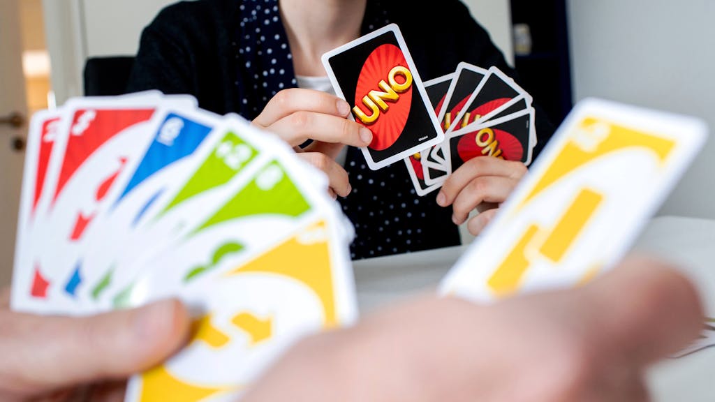 Eine Frau hält während einer Spielrunde die bunten Spielkarten des Kartenspiels „Uno“ in den Händen.