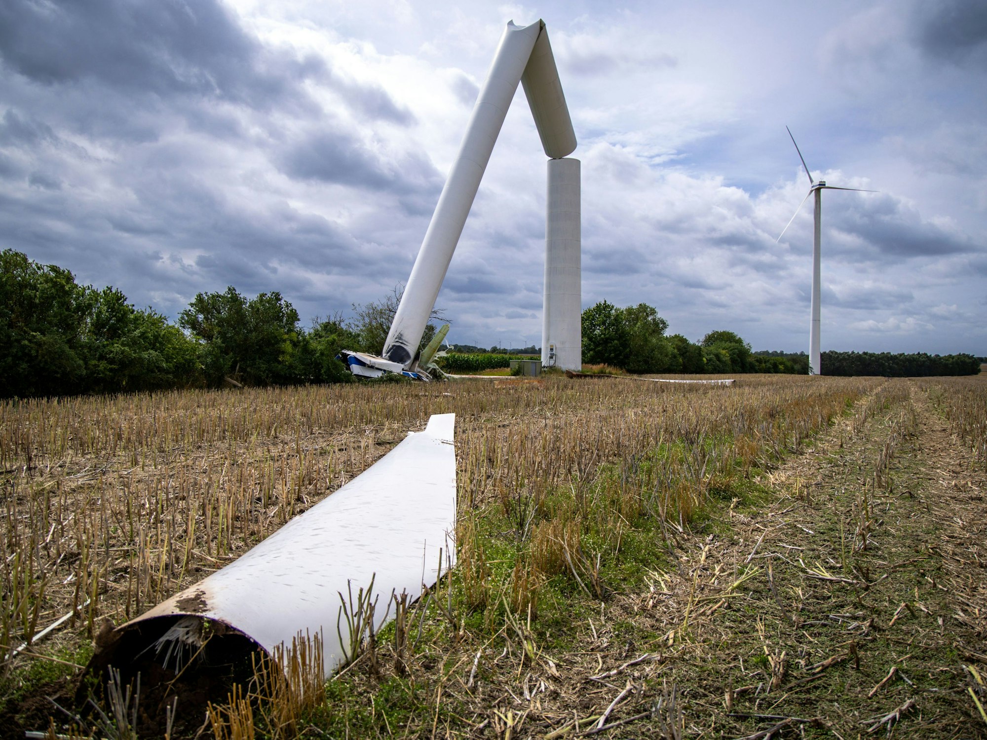 Ein zerstörtes Rotorblatt liegt vor einem vom Sturm abgeknickten Windrad in Dölitz auf einem Feld.