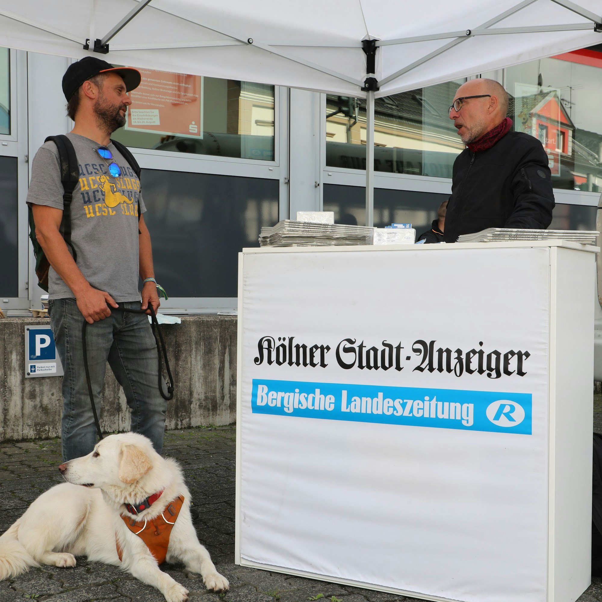 Johannes Thies mit Hund Baschko steht am Infostand der Lokalredaktion bei Redakteur Thomas Rausch.