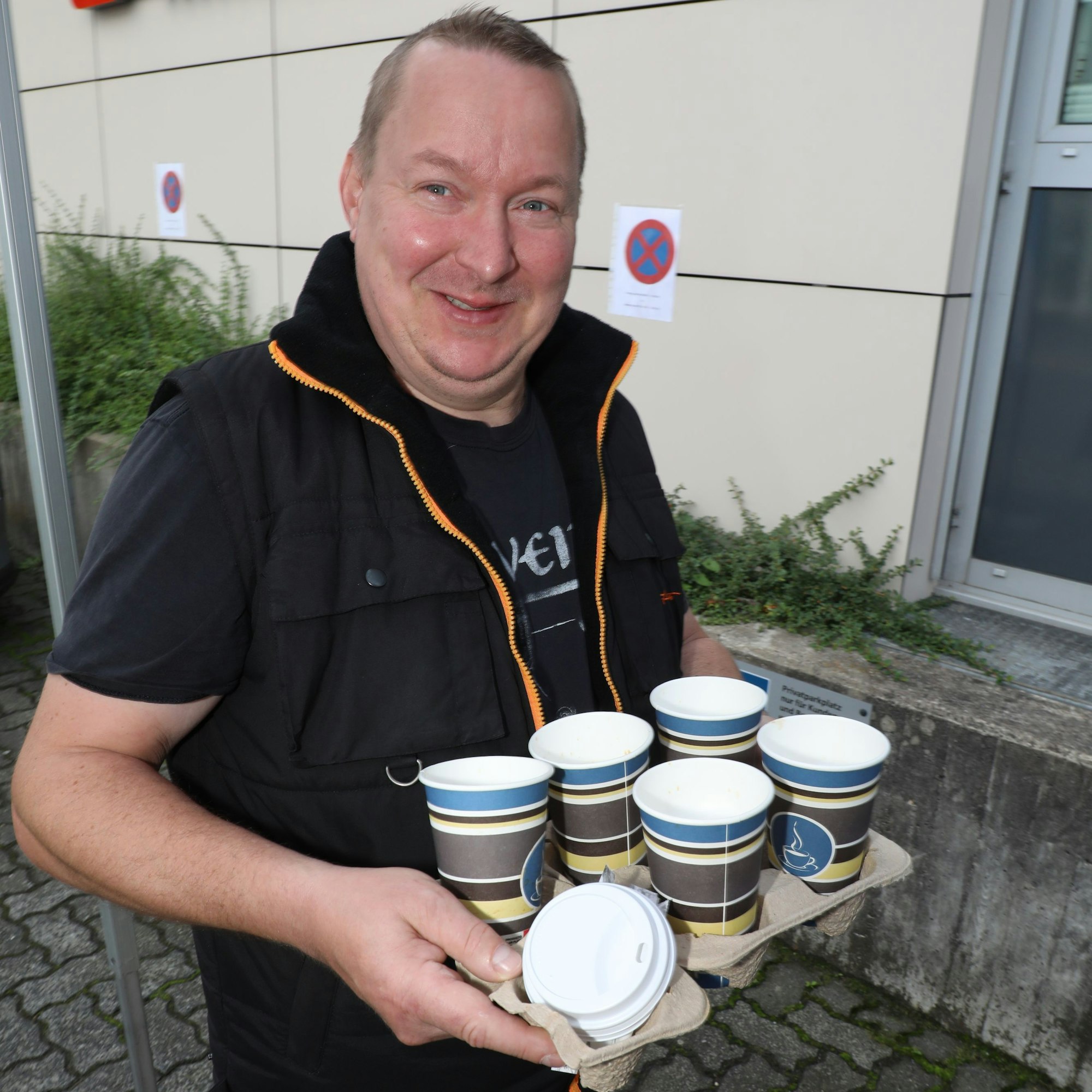 Simon Stachowiak trägt ein Tablett mit Kaffeebechern.