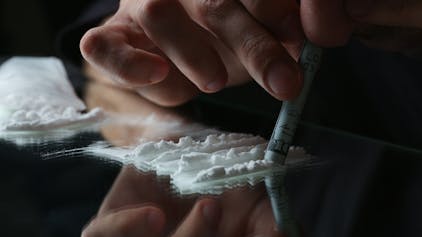 Eine Person zieht eine Line Kokain durch einen Geldschein