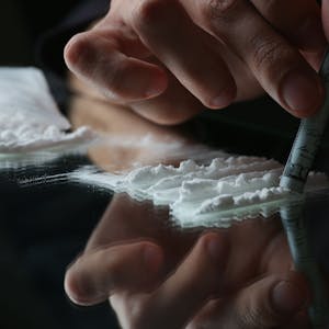 Eine Person zieht eine Line Kokain durch einen Geldschein