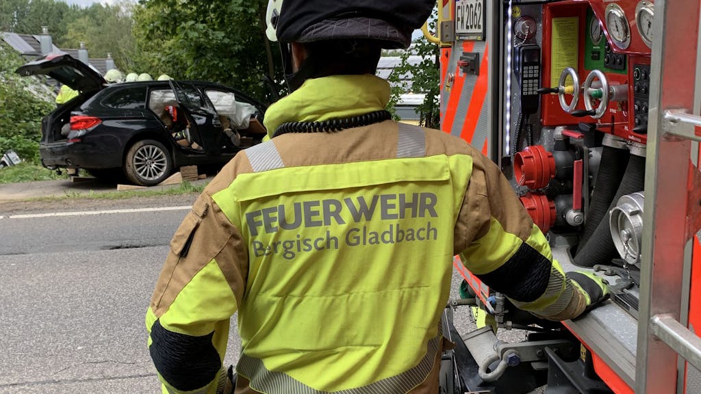 Die Feuerwehr Bergisch Gladbach am Unfallort in Moitzfeld. Einsatzkräfte durchsuchen den beschädigten BMW.