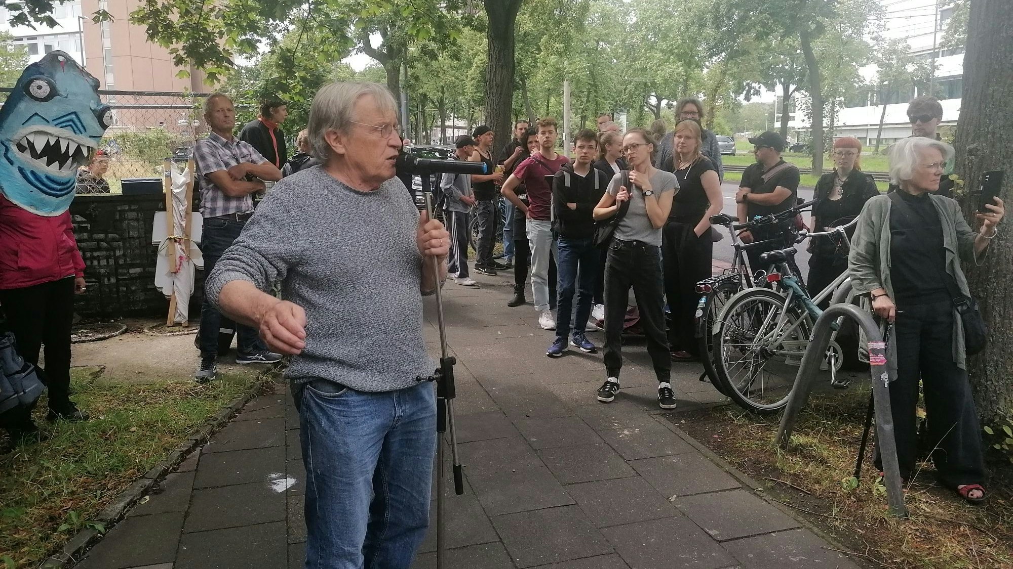 Mann, der vor Menschenmenge auf der Straße in ein Mikrofon spricht