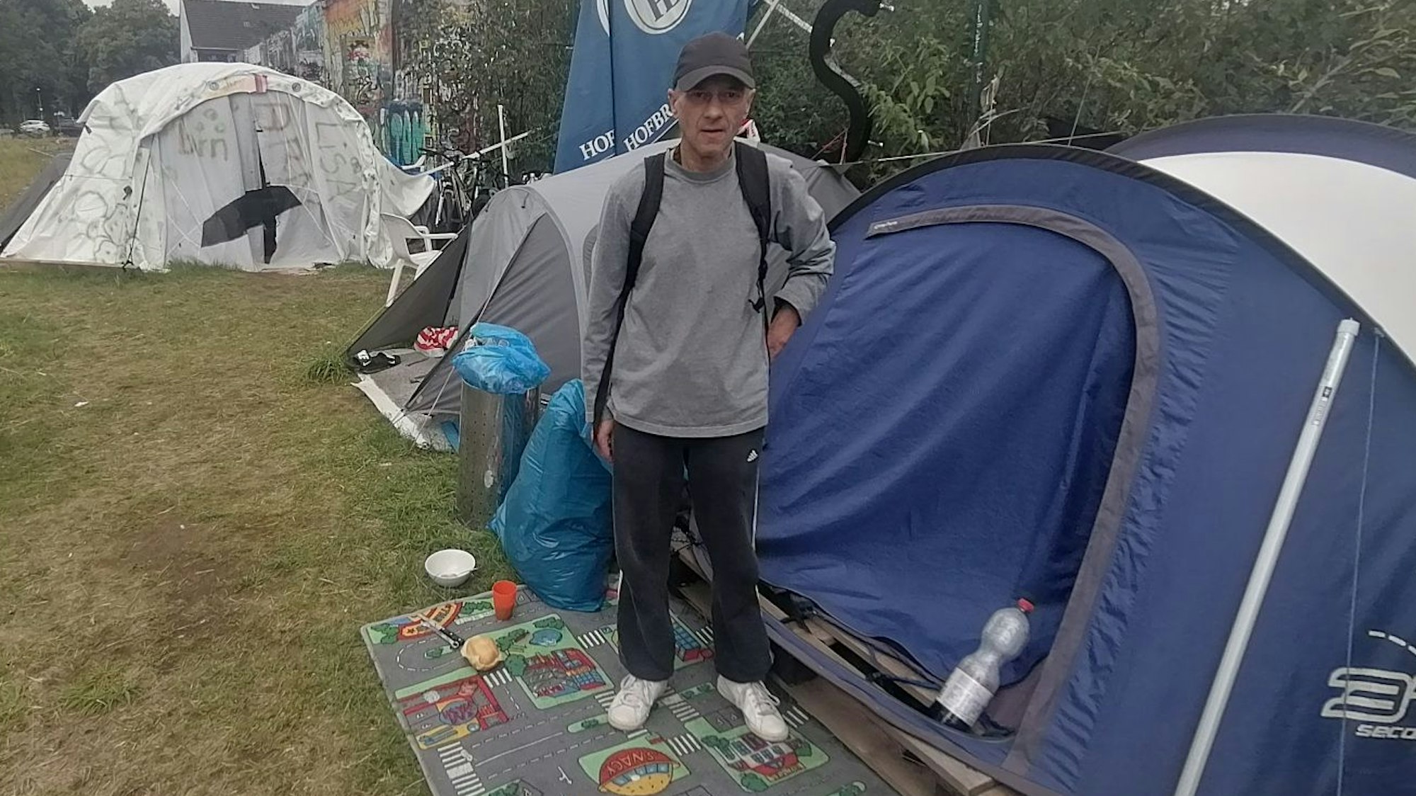 Junger Mann, der vor einem Zelt steht