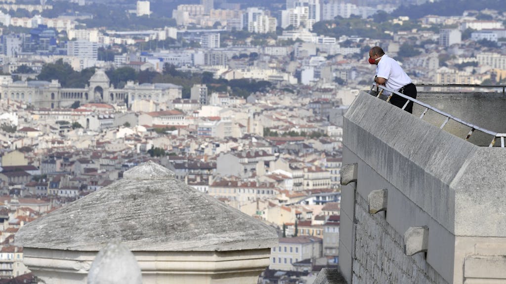 Ein Sicherheitspersonal, das eine schützende Gesichtsmaske trägt, genießt den Blick auf die Stadt von der Terrasse der Basilika Notre Dame de la Garde in Marseille, hier im Oktober 2020.&nbsp;