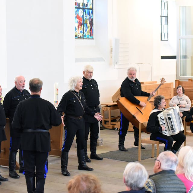 Schwarz gekleidete Sänger und Musiker treten vor Publikum in der Wiehler Kirche auf.