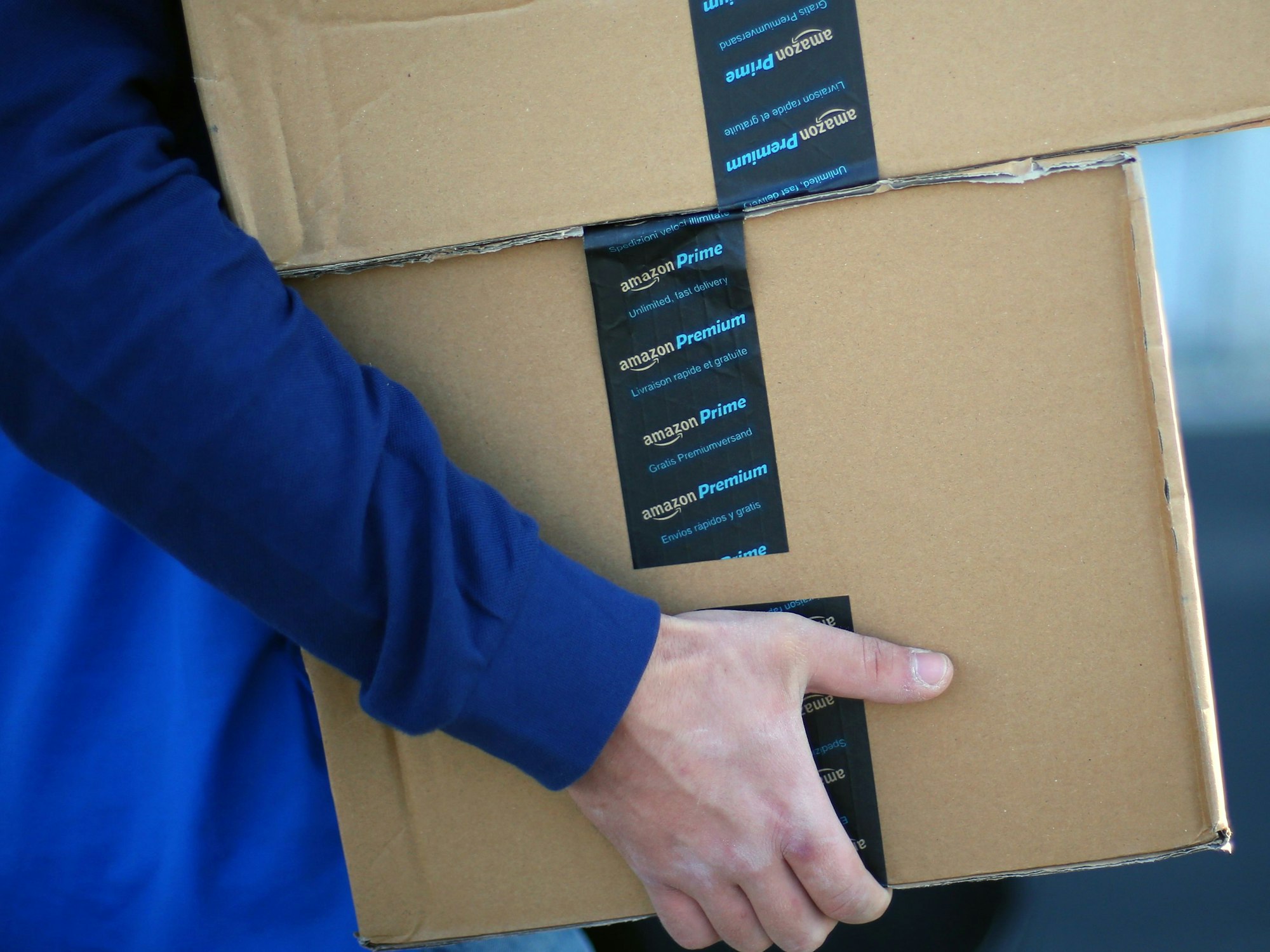Ein Mitarbeiter trägt Pakete mit einem Aufkleber „Amazon Premium“.