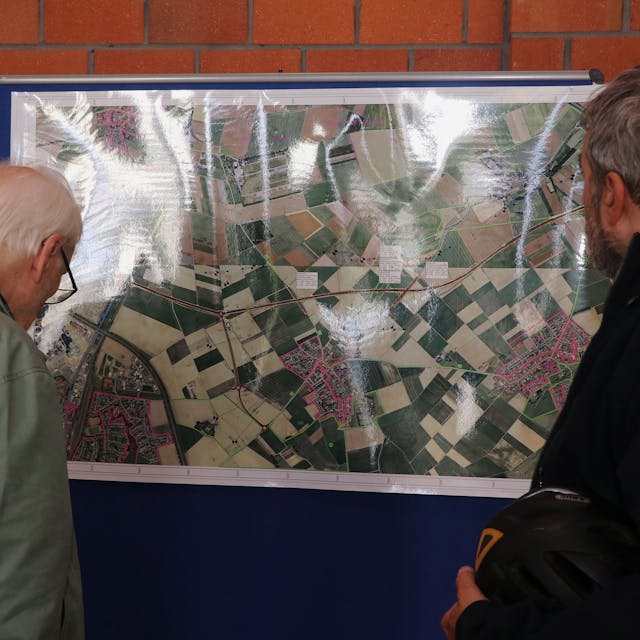 Zwei Männer schauen sich eine Karte an, auf der die geplante Landesstraße eingezeichnet.