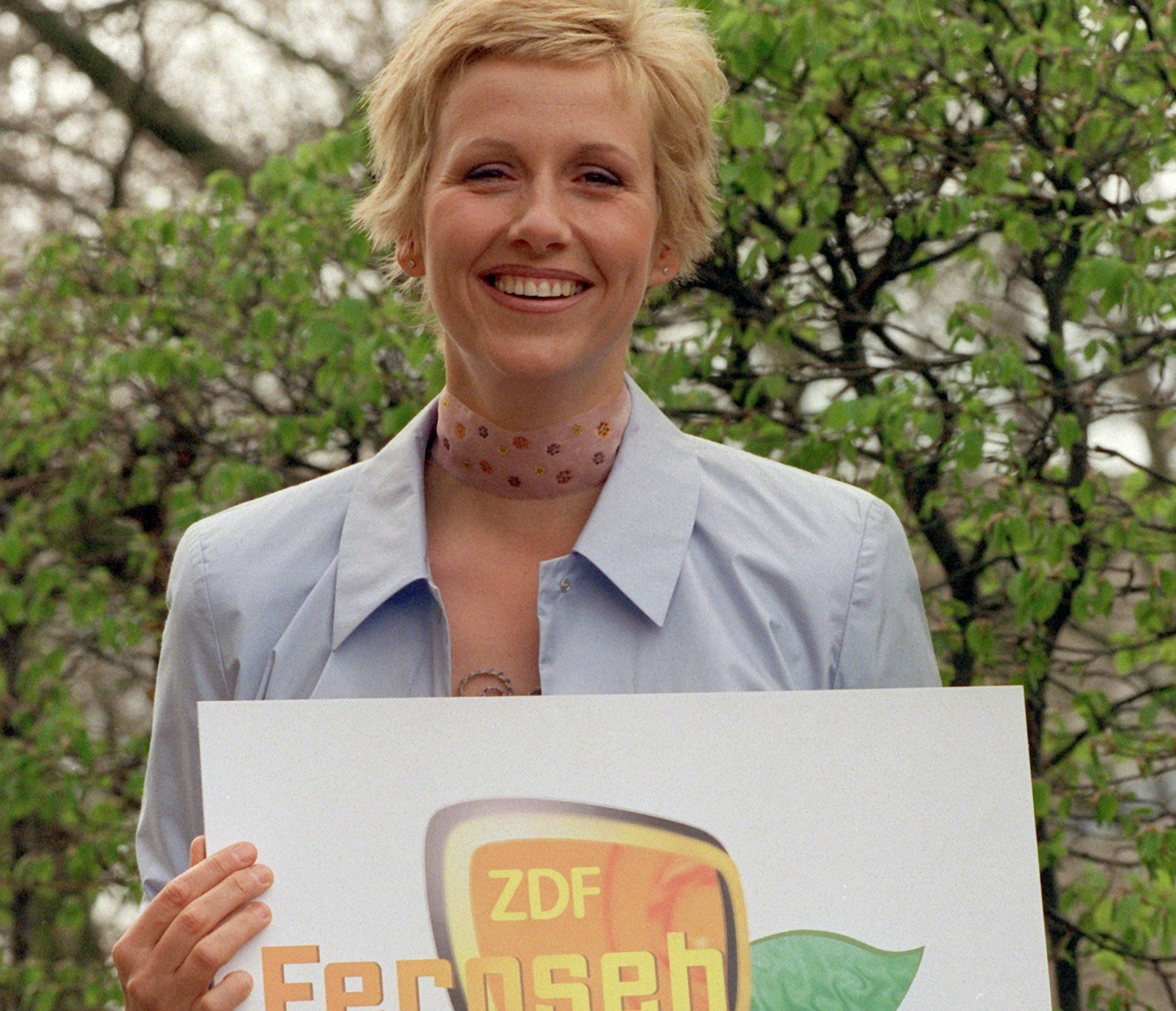 Die damals neue Moderatorin des «Fernsehgartens» des ZDF, Andrea Kiewel, hält lachend ein Schild mit dem Logo ihrer Show in den Händen.