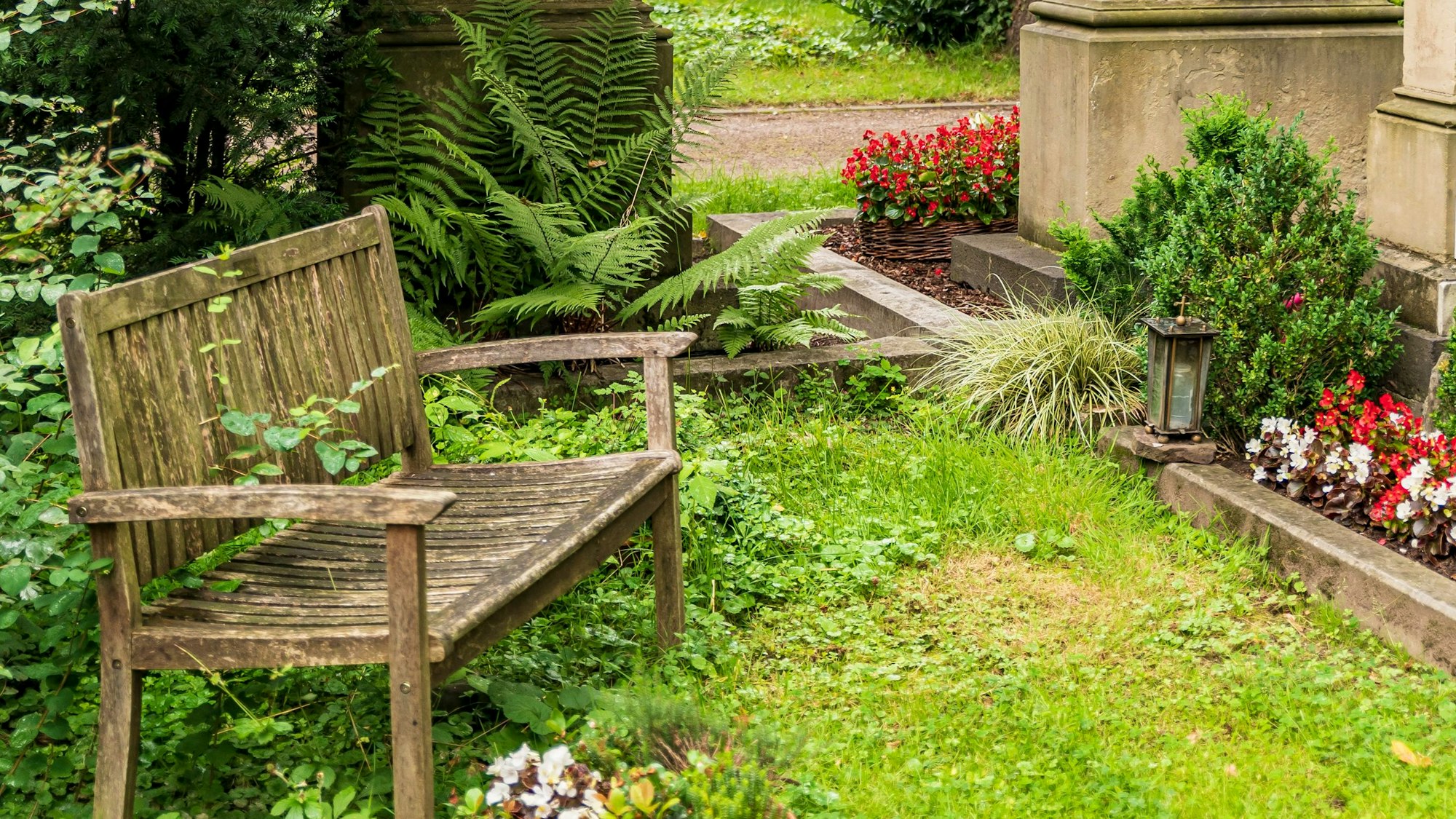 Eine Holzbank steht an einem Grab auf dem Melatenfriedhof.