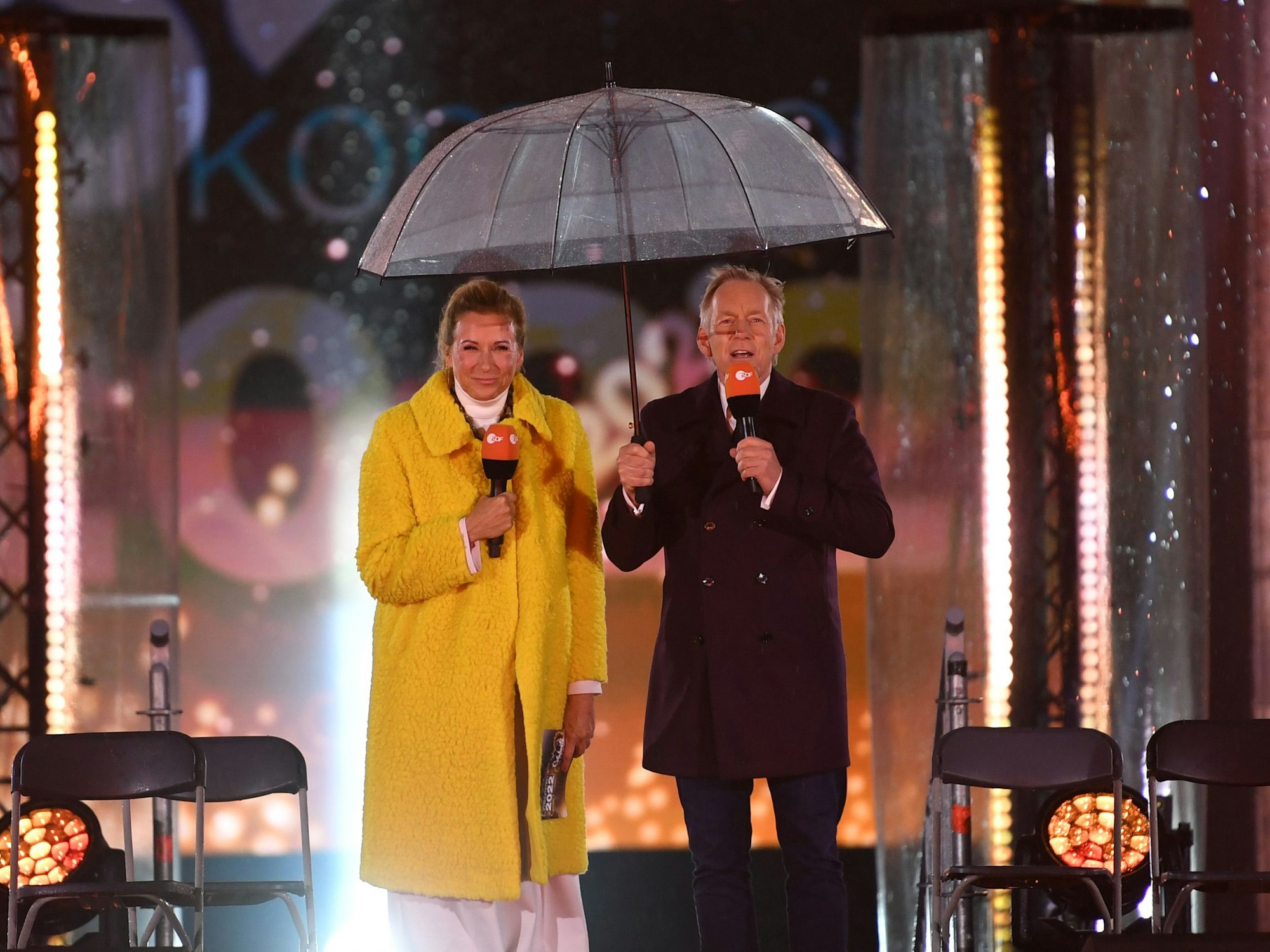 Die Moderatoren Andrea Kiewel und Johannes B. Kerner stehen bei der Silvesterfeier vom ZDF vor dem Brandenburger Tor mit einem Schirm auf der Bühne.