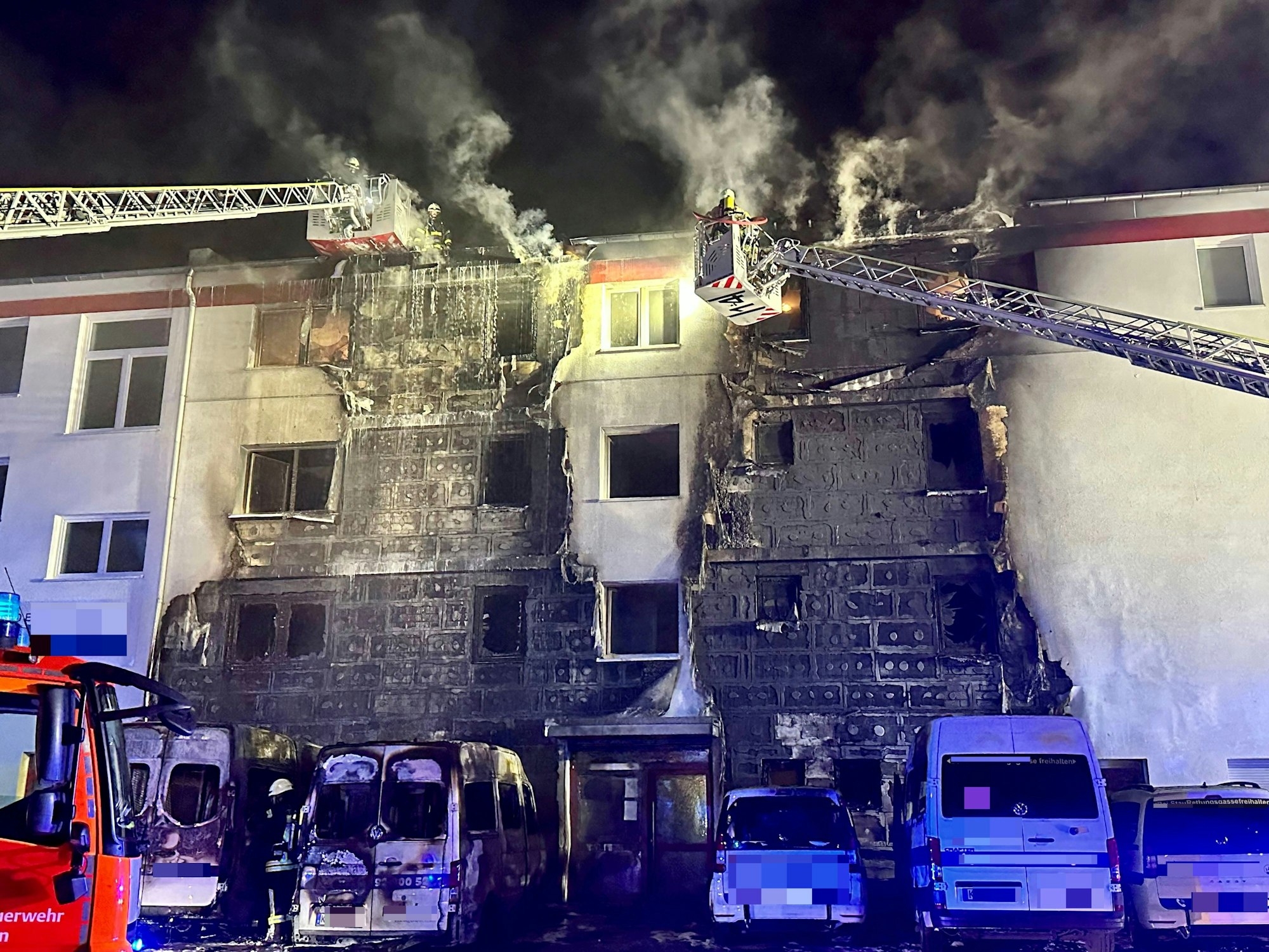 Kölner Feuerwehr löscht mit zwei Drehleitern eine brennende Hausfassade.