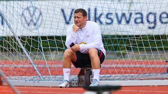 Max Eberl sitzt am Rande des Trainingsplatzes von RB Leipzig.