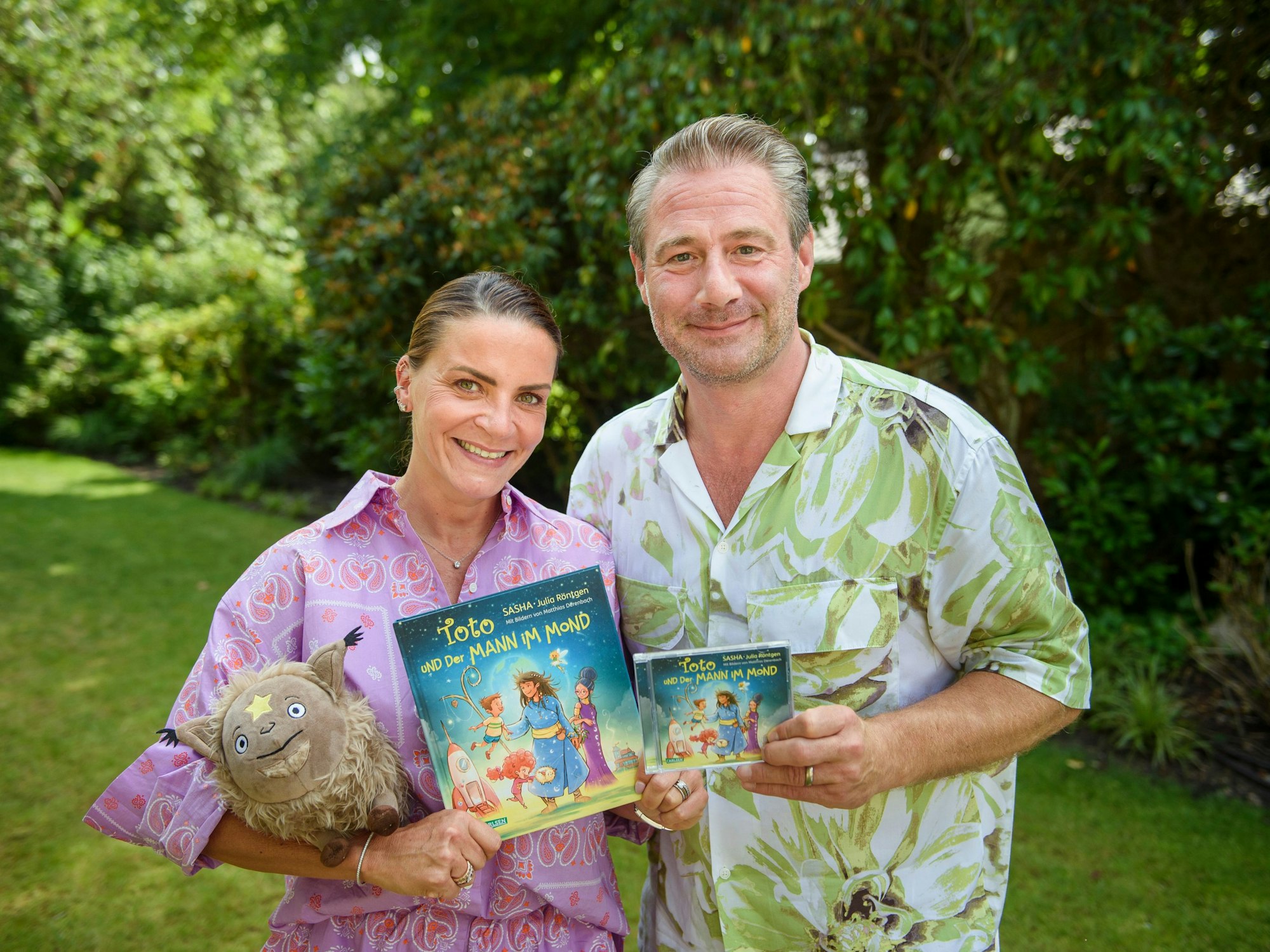 Sasha und seine Frau Julia Röntgen präsentieren das Kinderbuch und das Album zu „Toto und der Mann im Mond“ im Garten ihres Grundstücks.