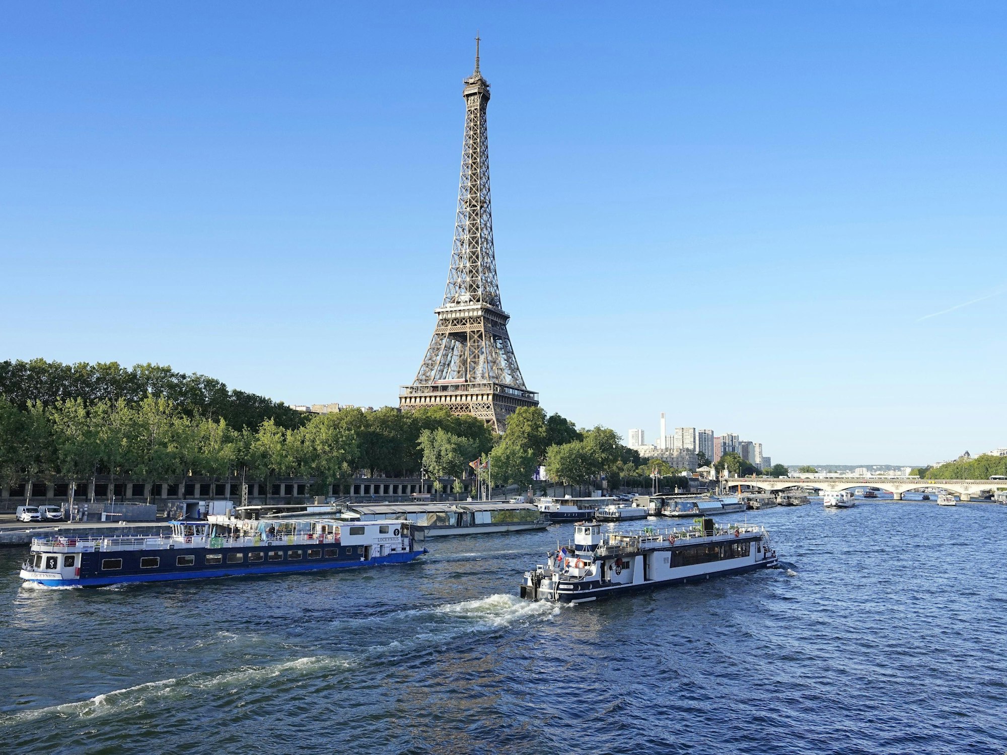 Ein Boot und ein Lastkahn fahren am 17. Juli 2023 vor dem Eiffelturm auf der Seine in Paris.