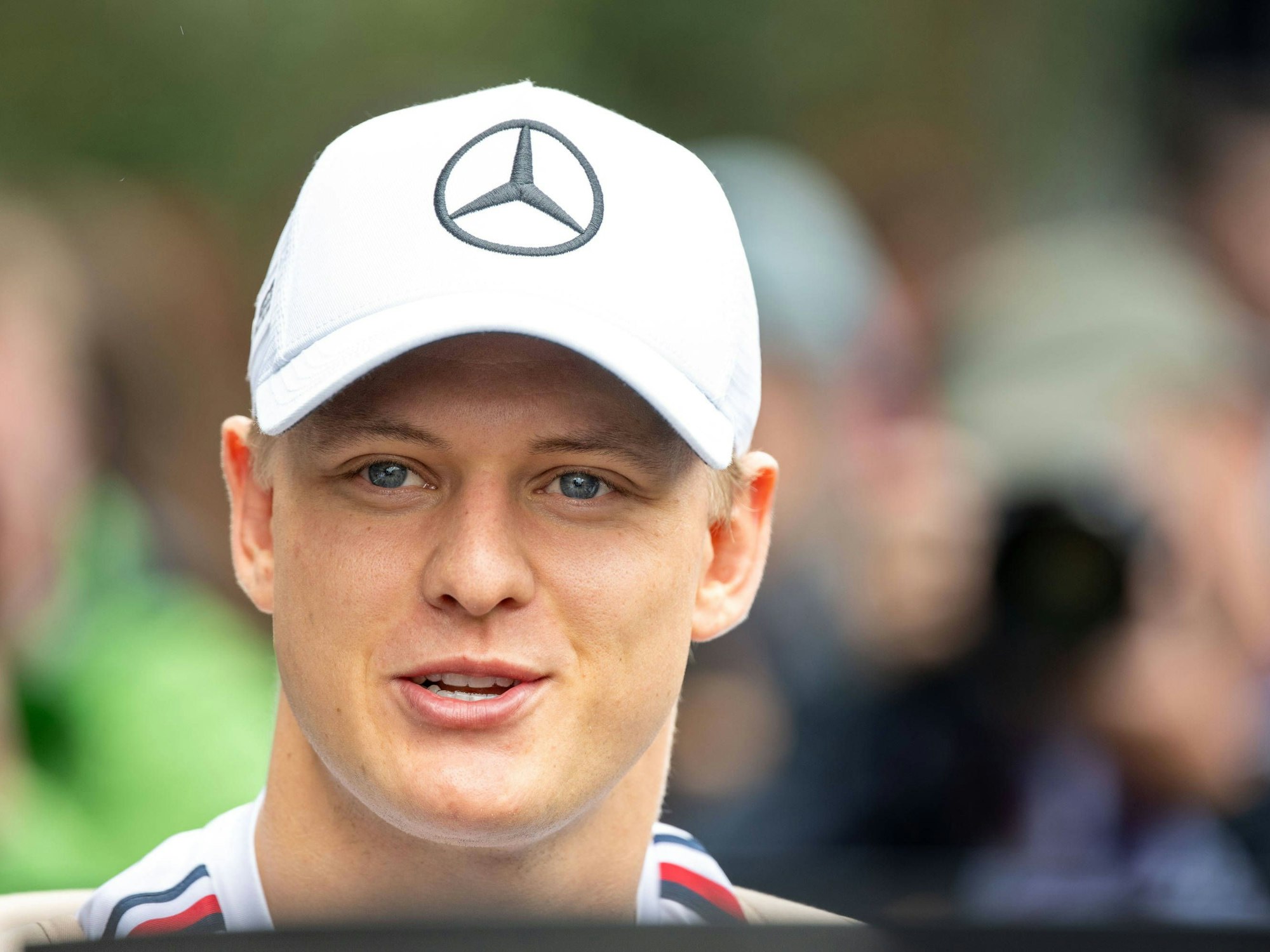Mick Schumacher lächelt. Er trägt eine Mercedes-Kappe.