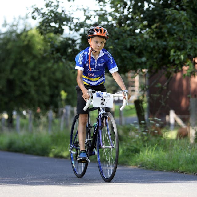 Ein Kind ist auf einem Rennrad unterwegs.